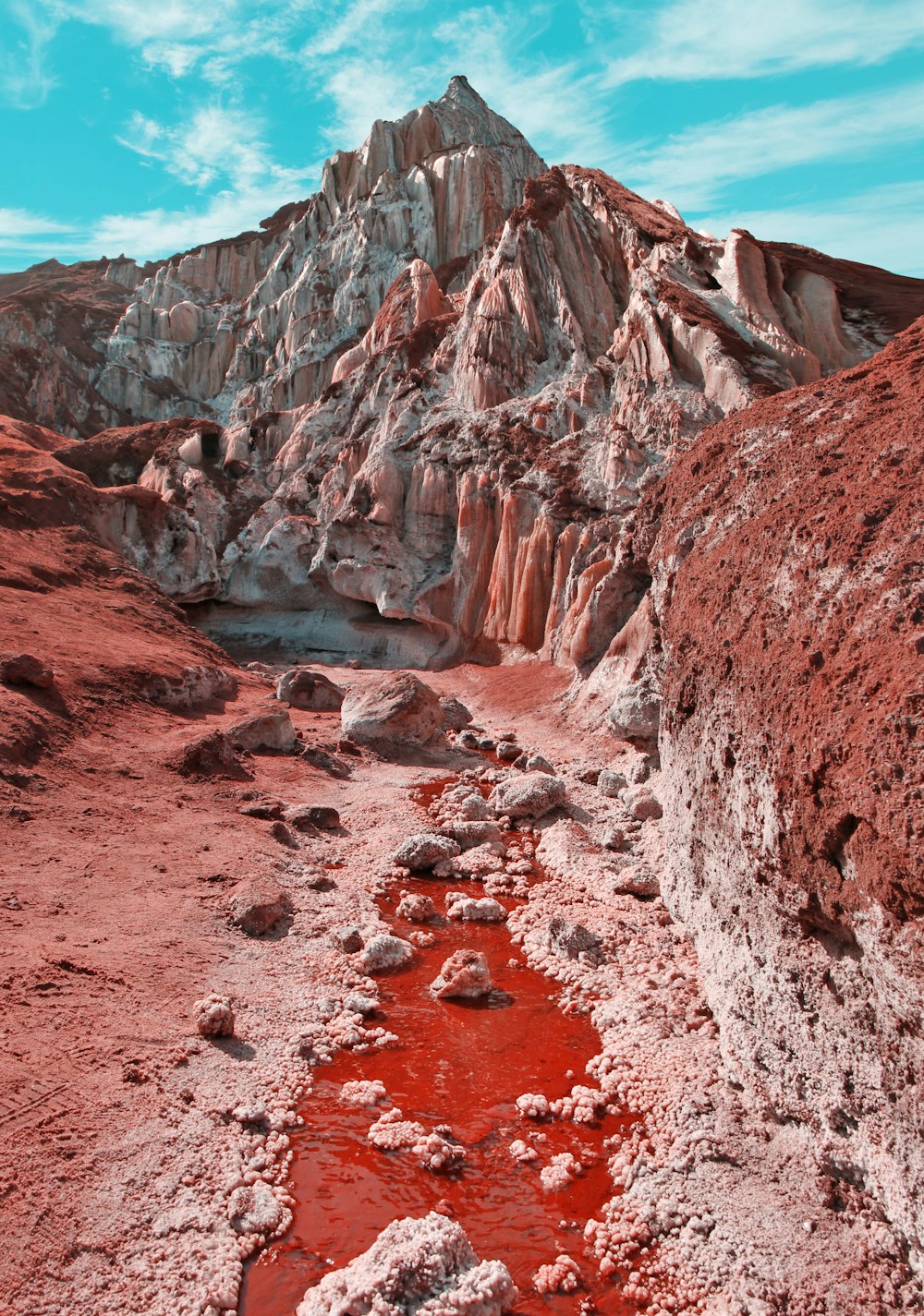 a rocky mountain with a red pool of water
