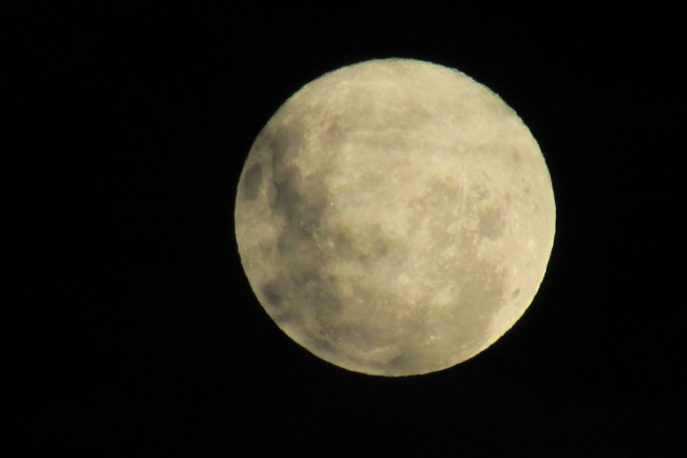 a full moon is seen in the dark sky