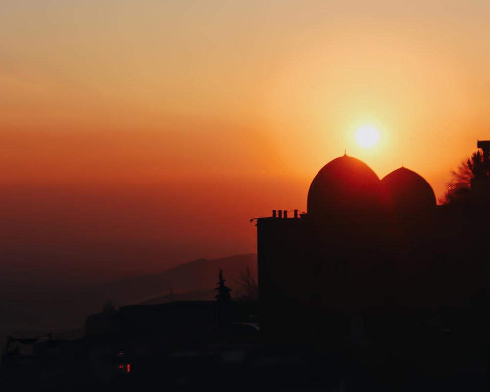 the sun is setting behind a building with a dome