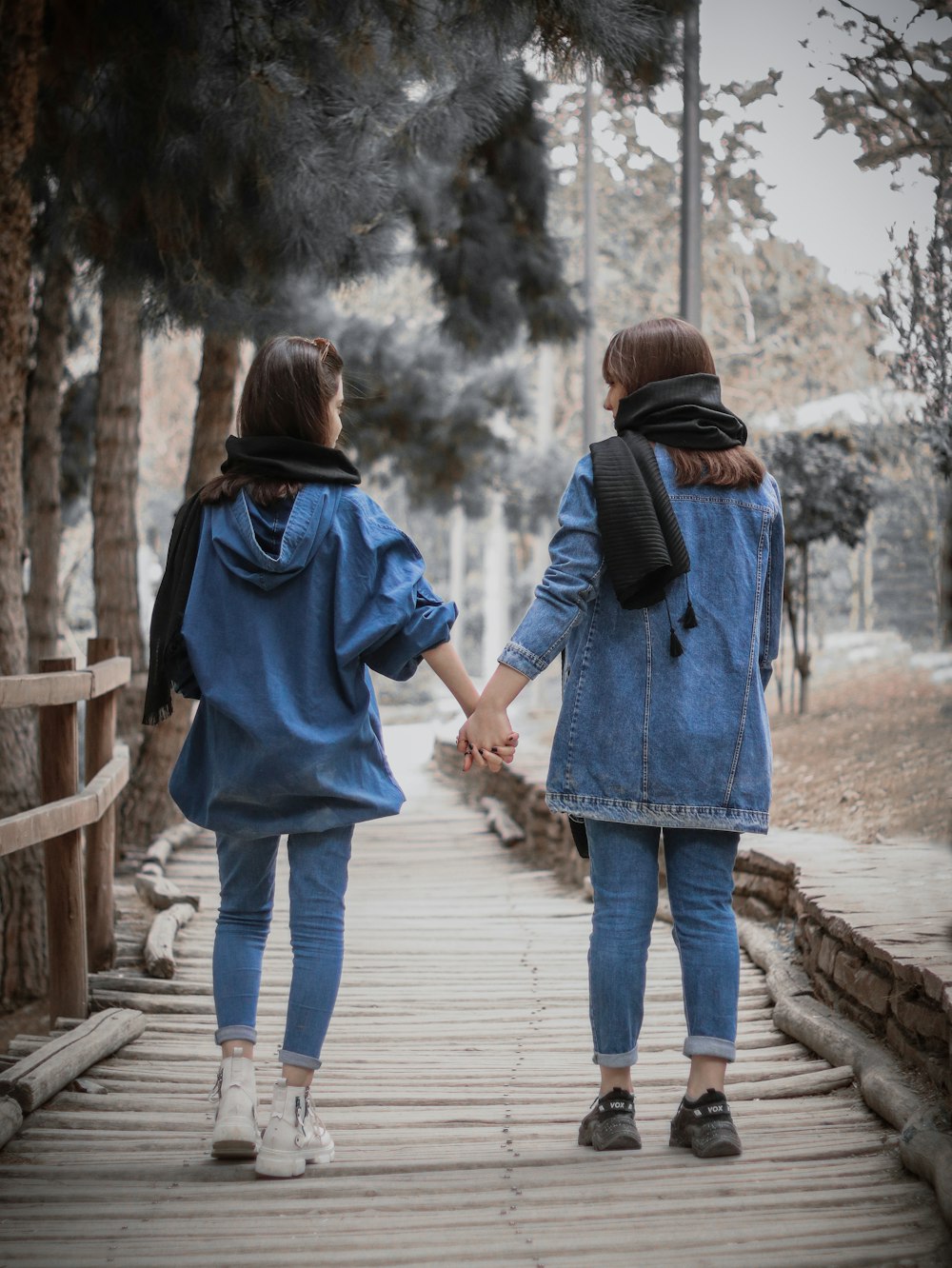 two women walking down a wooden walkway holding hands
