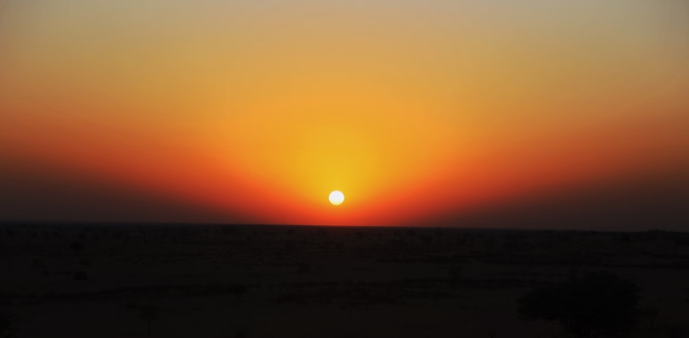 the sun is setting in the sky over the desert