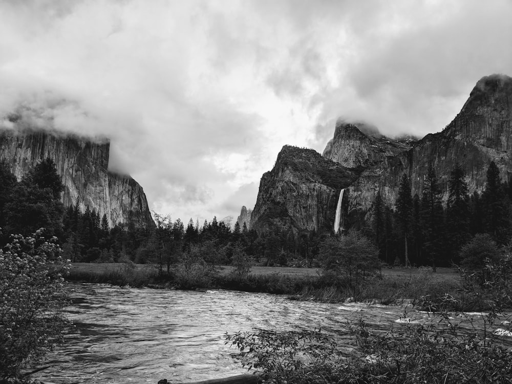 a black and white photo of a waterfall and mountains