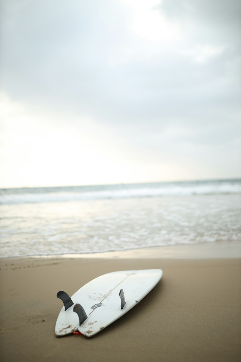 a surfboard laying on the sand of a beach