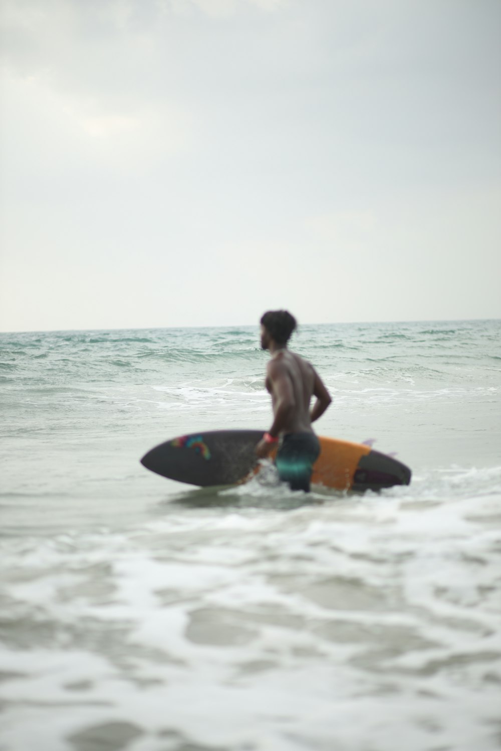 a man standing in the ocean holding a surfboard