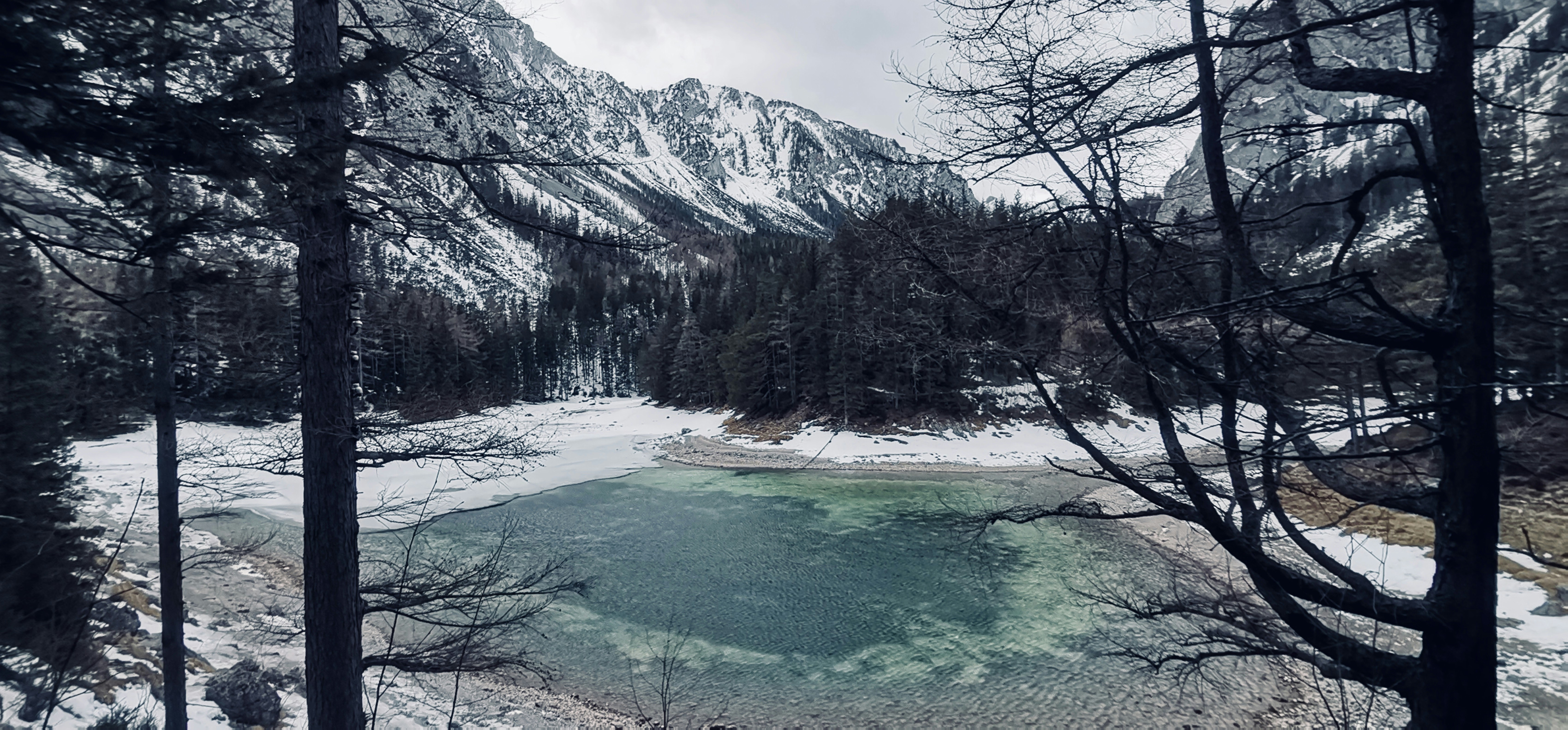 un lac entouré de montagnes enneigées et d’arbres