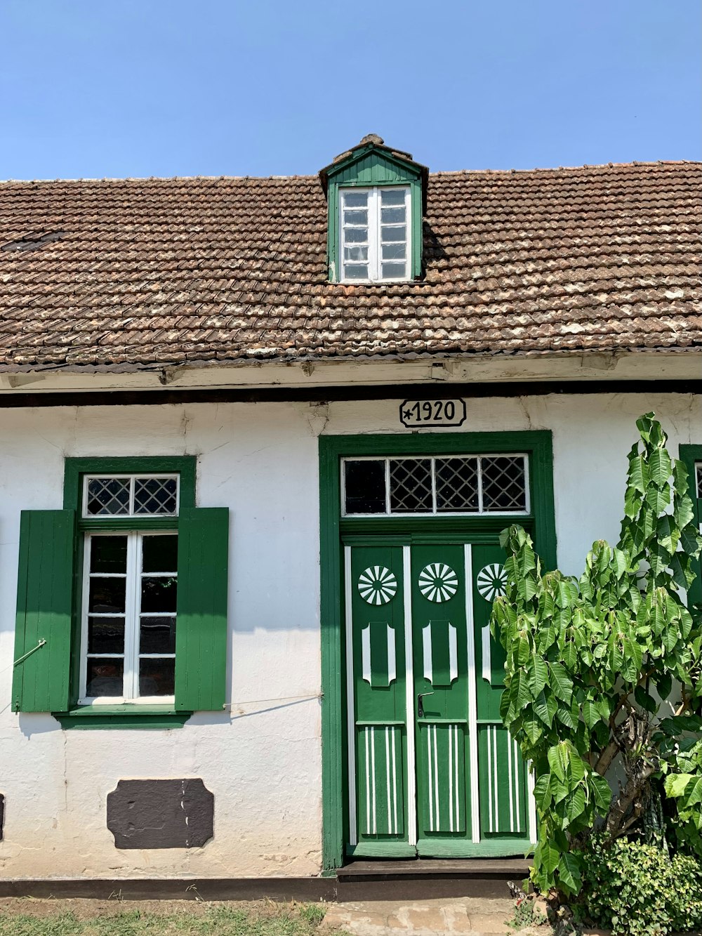 a white house with green shutters and a brown roof