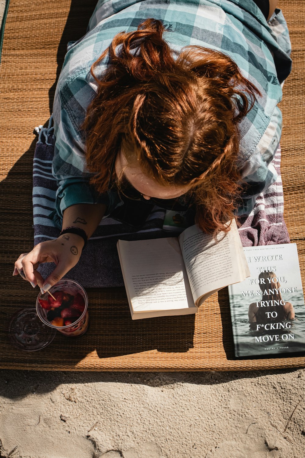 a woman reading a book and drinking a drink