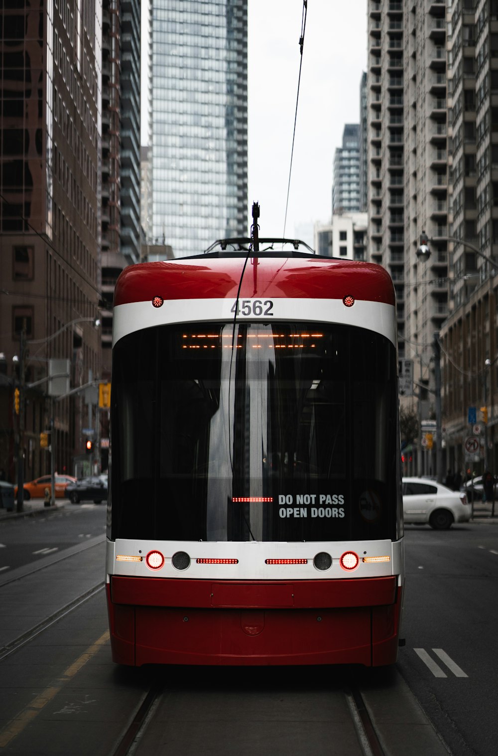 a red and white bus driving down a street next to tall buildings