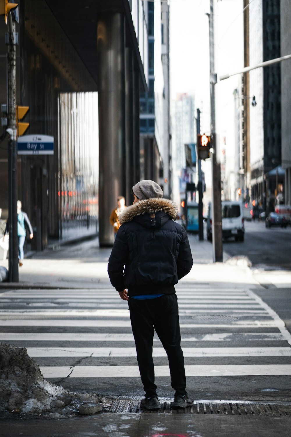 a man standing at a crosswalk in the middle of a city