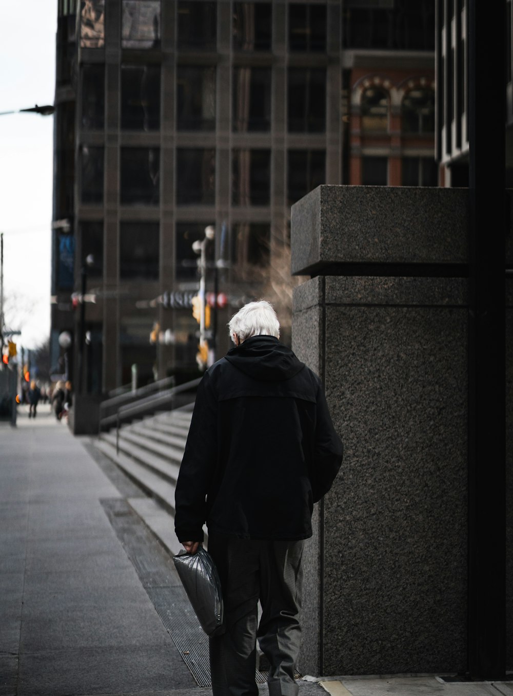 a man walking down a sidewalk next to a tall building