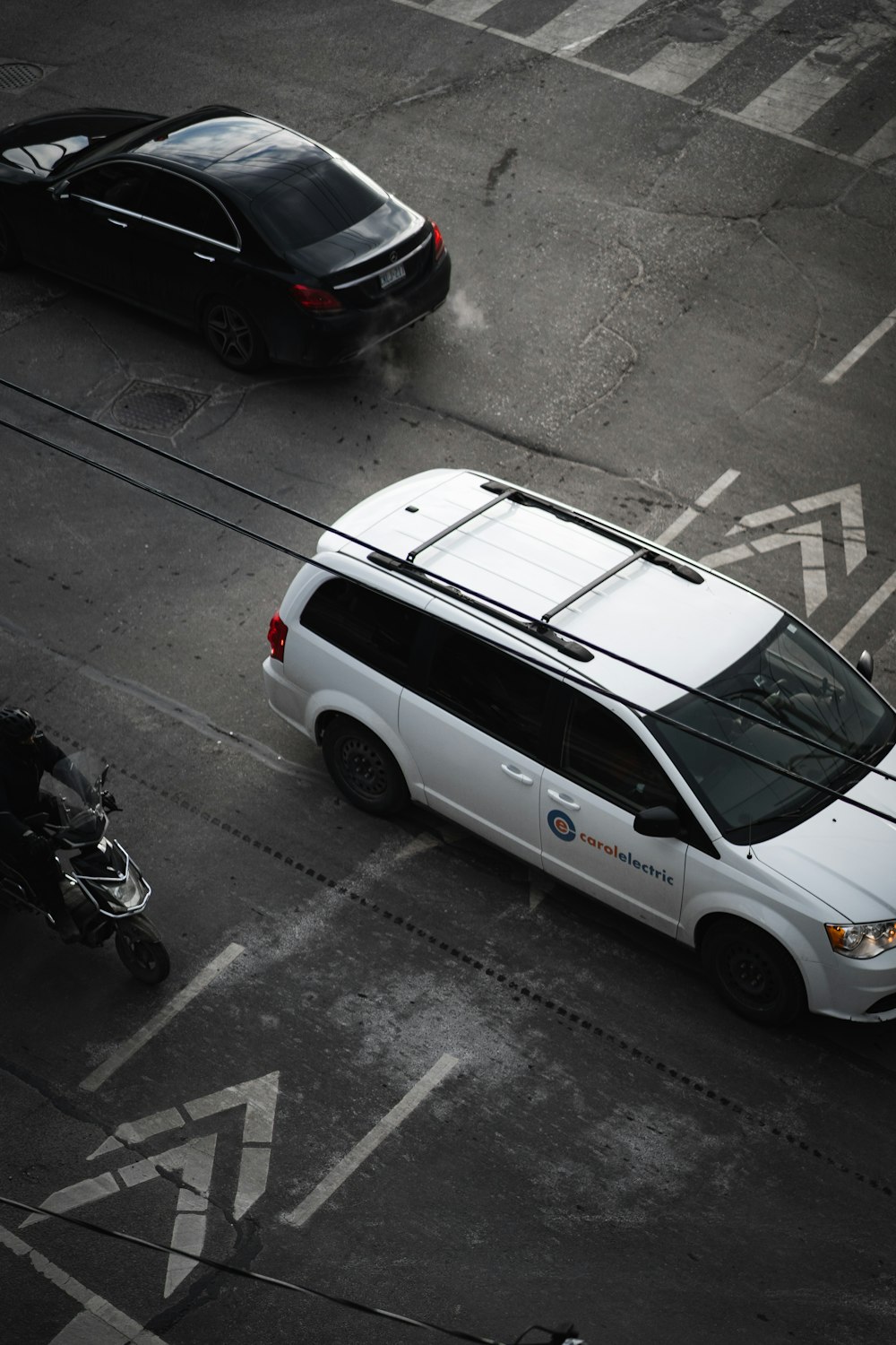 a white van driving down a street next to a motorcycle