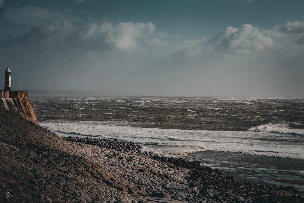 a lighthouse sitting on top of a sandy beach next to the ocean