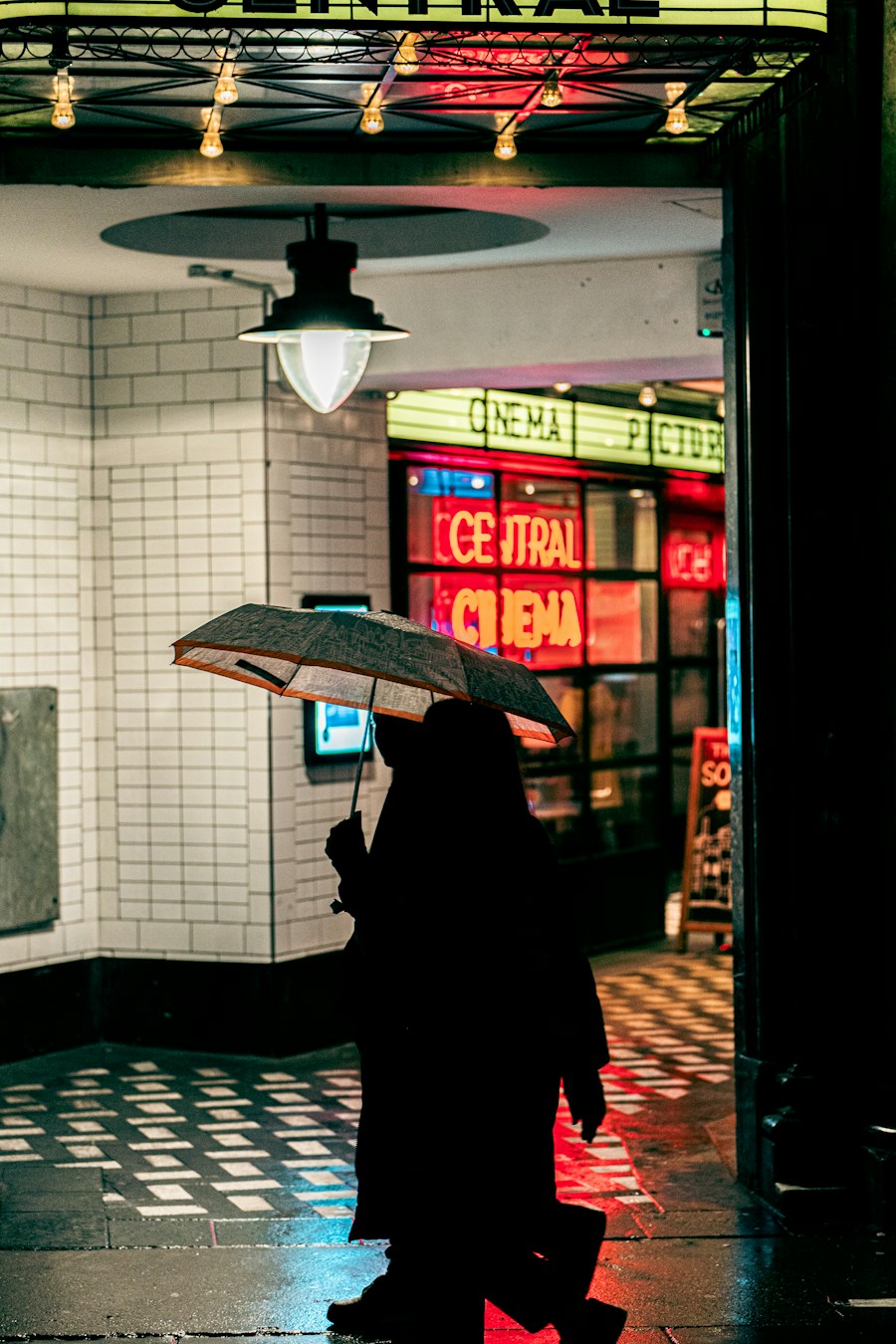 Person with an umbrella on a neon-lit London street at night, placeholder city culture image