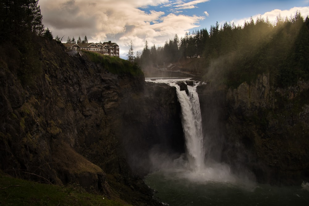 a large waterfall with a house in the background