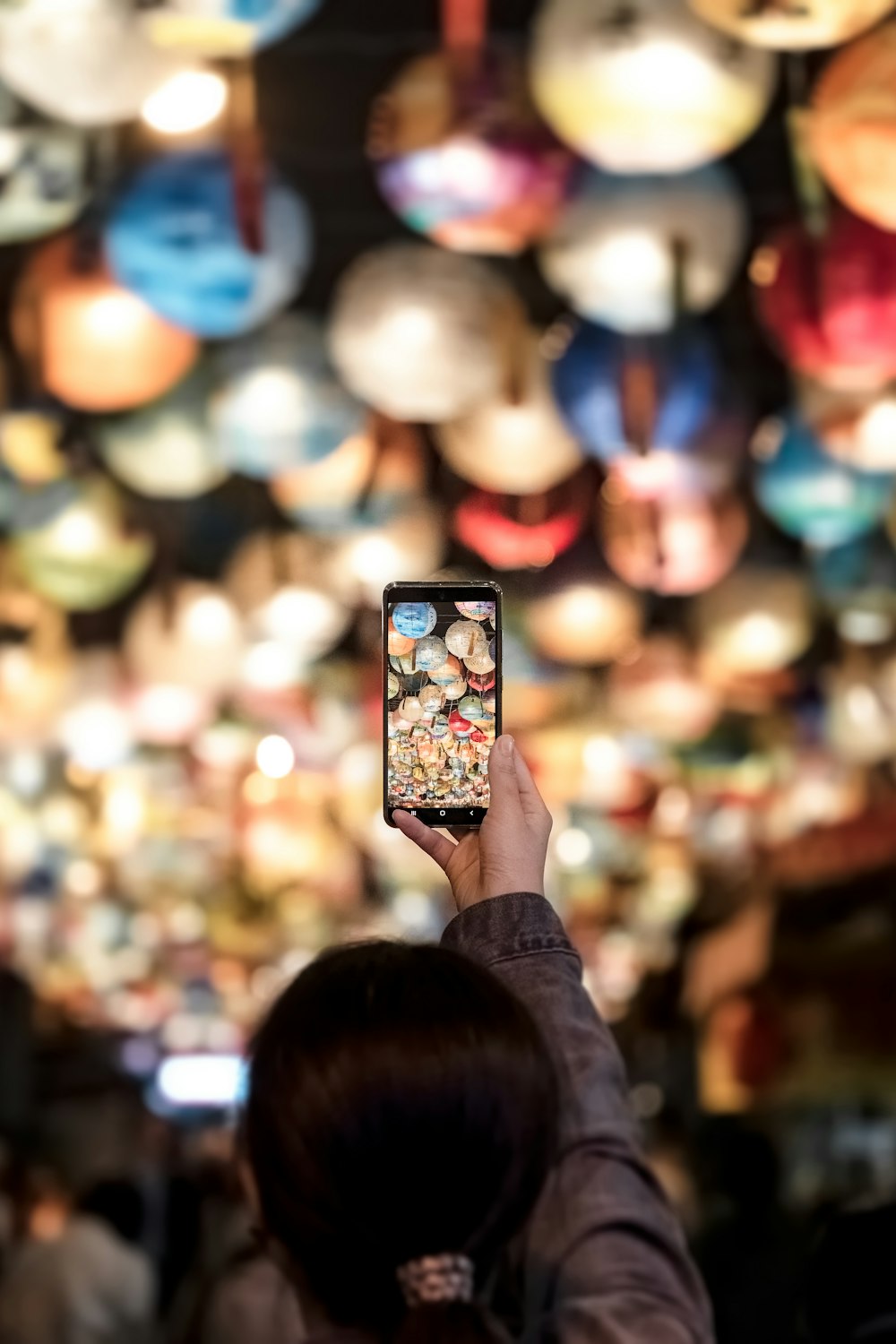 a person holding up a cell phone in front of a ceiling of lights