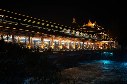 a lit up building next to a body of water