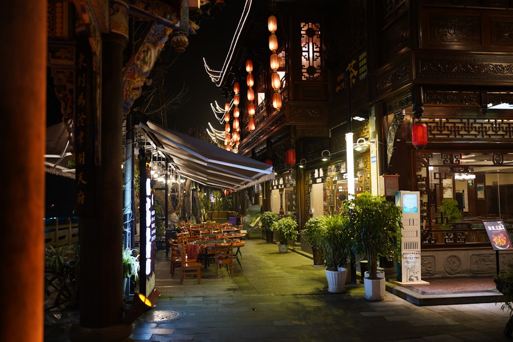 a city street at night with tables and chairs