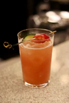 A colorful senoryta cocktail with a slice of lime and a straw, set on a sleek black surface.