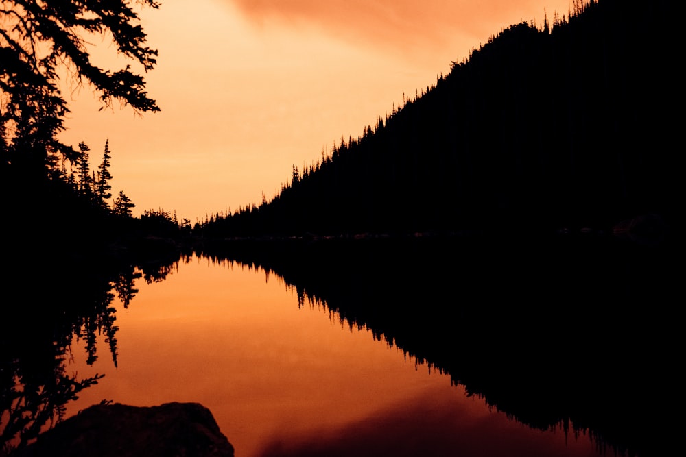 a lake surrounded by a forest under a cloudy sky