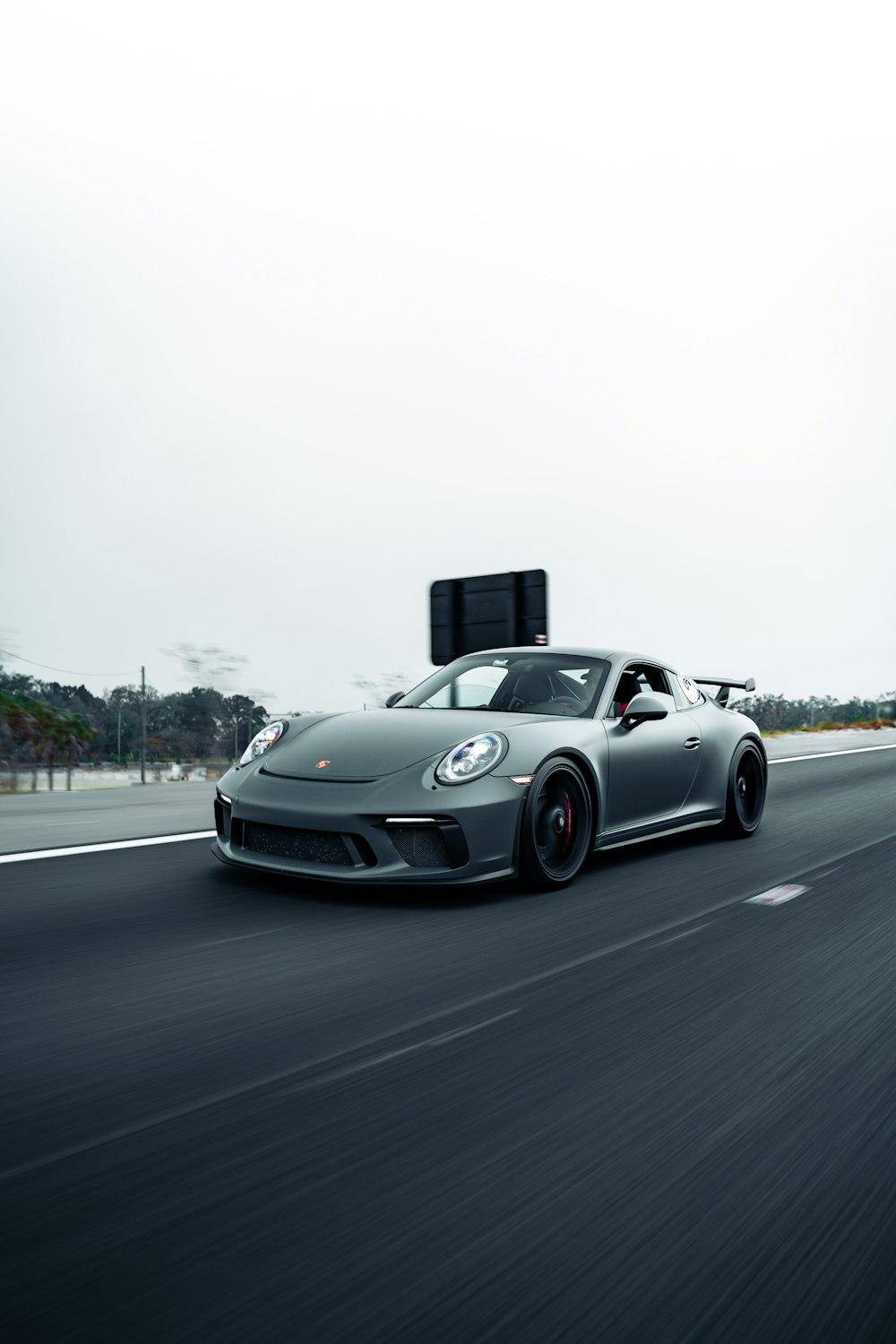 a silver sports car driving down a highway