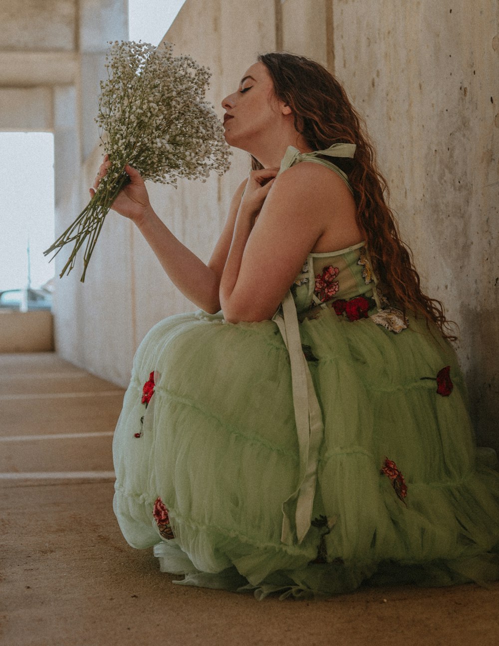 a woman in a green dress holding a bunch of flowers