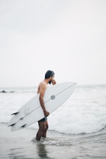 a man holding a surfboard walking into the ocean