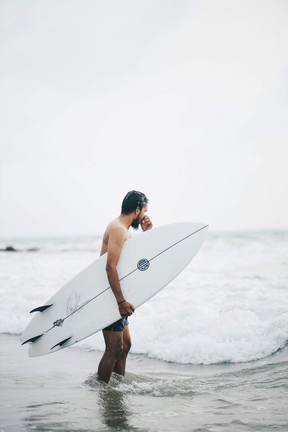 a man holding a surfboard walking into the ocean
