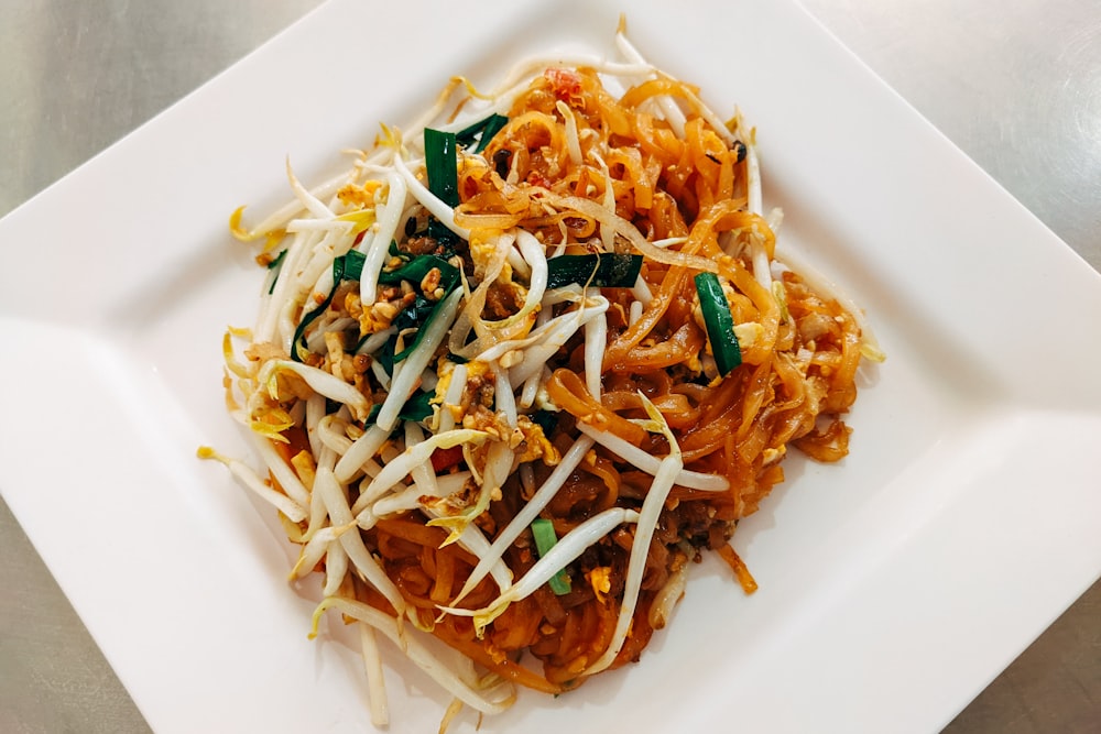 a white plate topped with noodles and vegetables