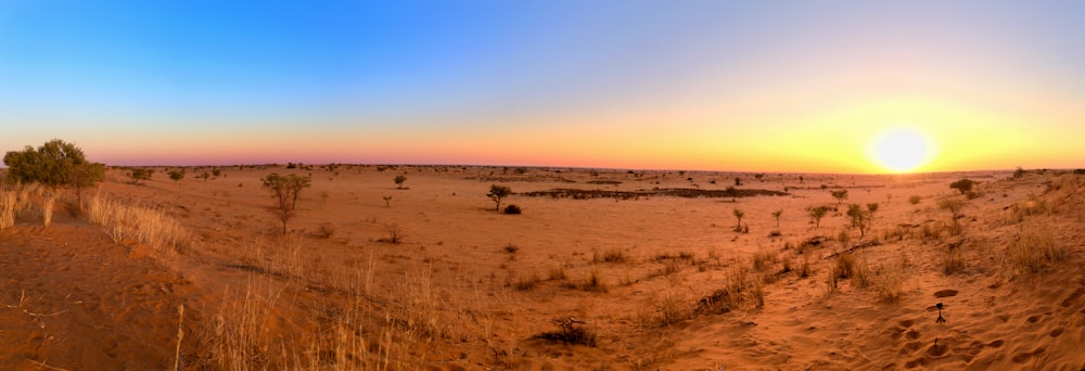 the sun is setting over a desert landscape