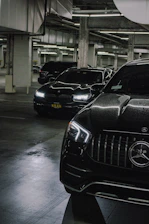 Modern BMW and Mercedes cars being serviced in a bright, clean garage with blue gradient lighting.
