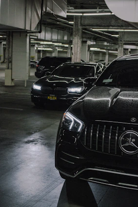 Modern BMW and Mercedes cars being serviced in a bright, clean garage with blue gradient lighting.