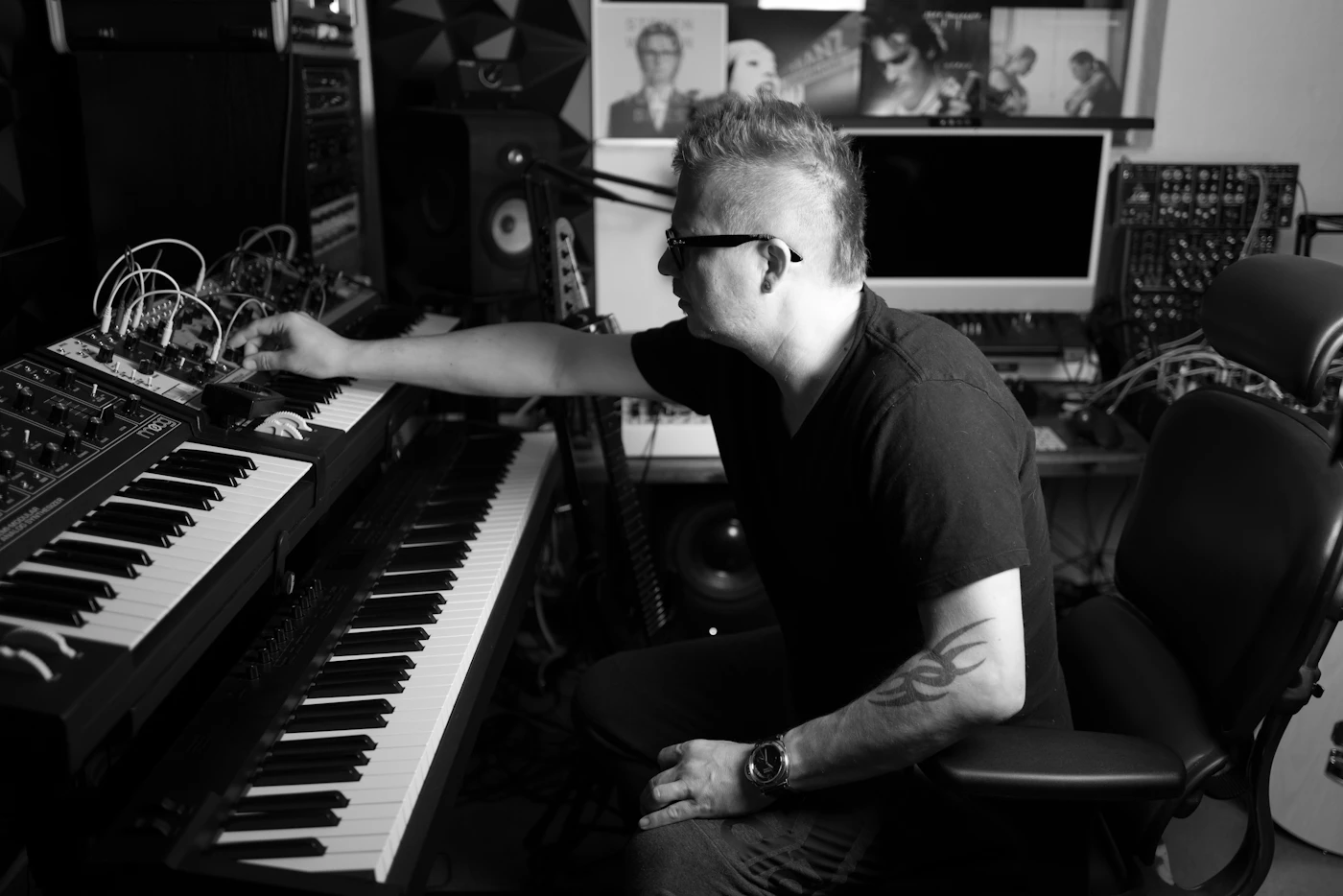 Musician sitting at a keyboard in a home studio