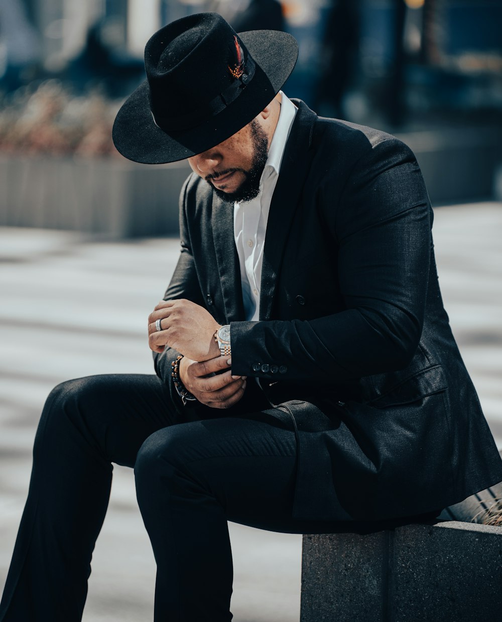 a man in a suit and hat sitting on a bench