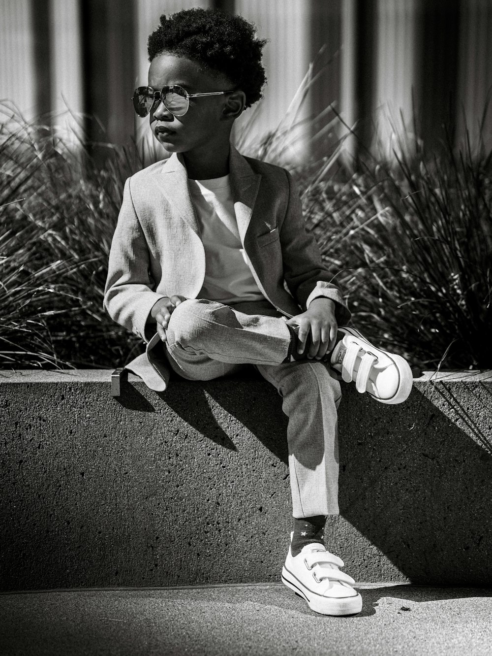 a black and white photo of a person sitting on a wall