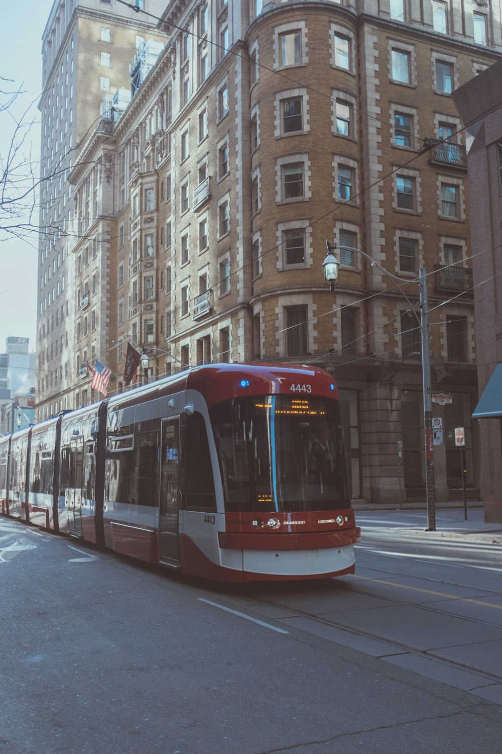 a red and white bus driving down a street next to tall buildings