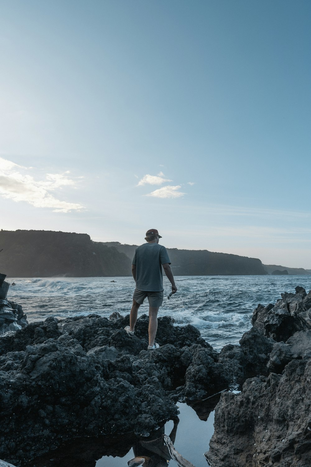 a man standing on top of a rocky beach next to the ocean