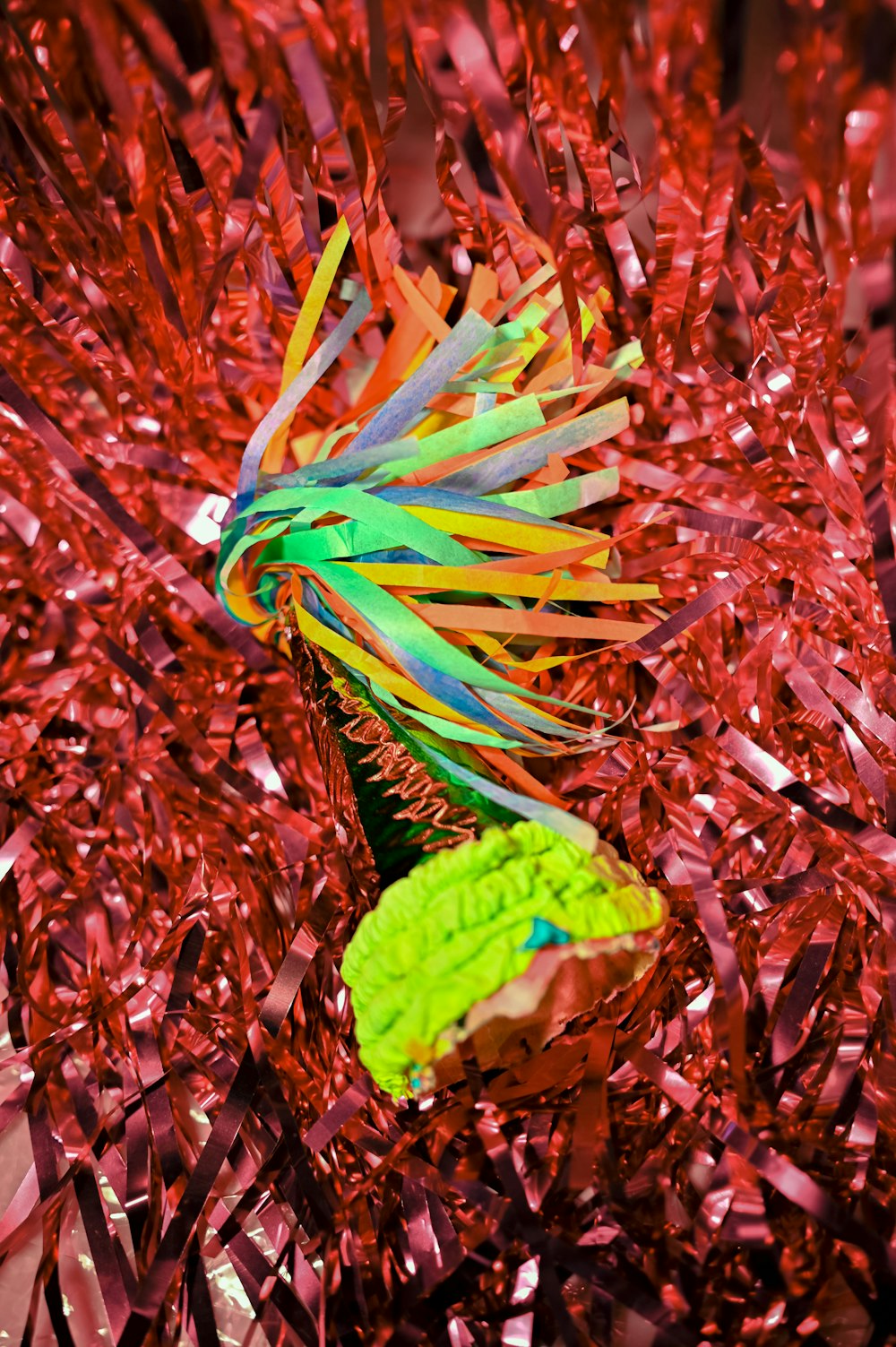 um pássaro multicolorido está empoleirado em uma planta vermelha