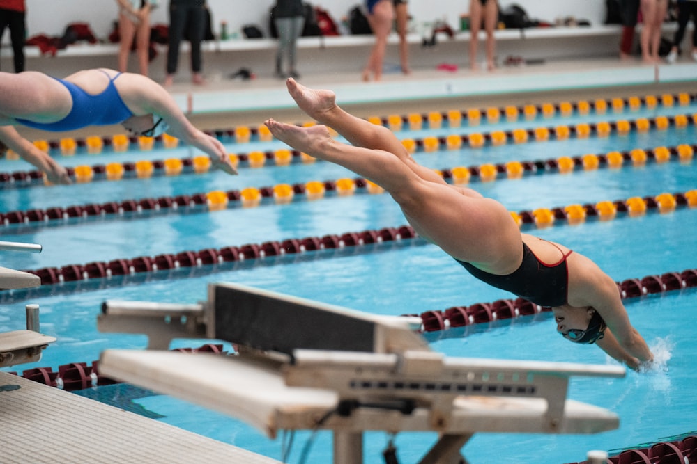 a man diving into a swimming pool while others watch