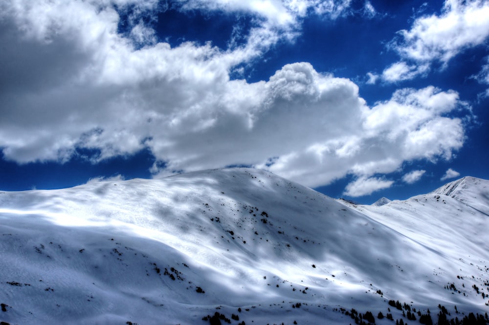 a snow covered mountain under a cloudy blue sky