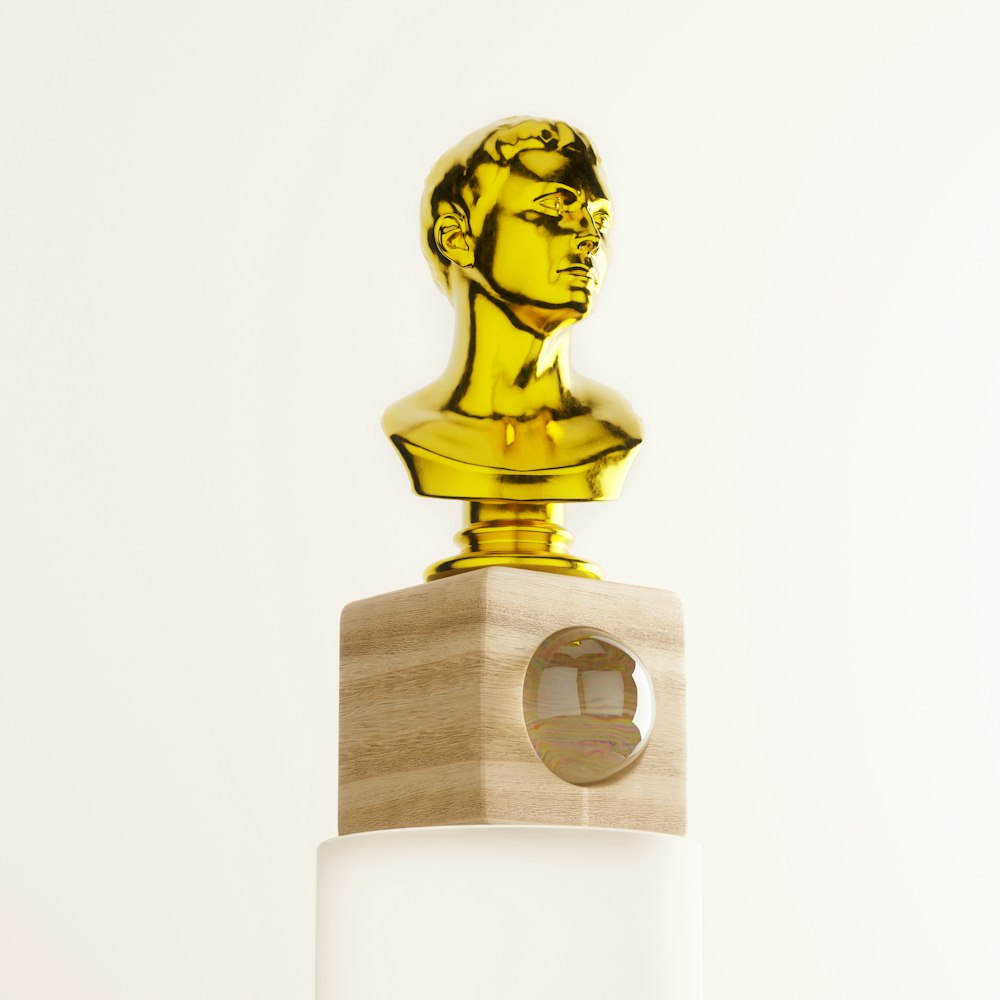 a golden statue on top of a white pedestal