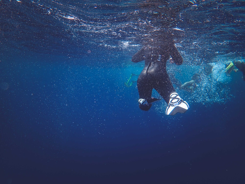a man in a wet suit swimming under water