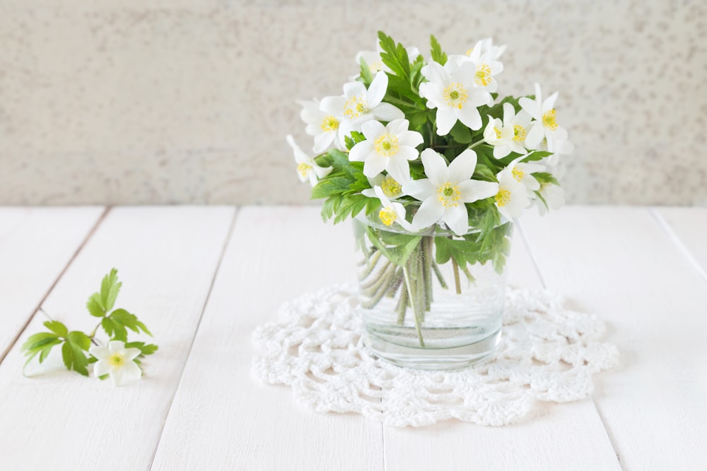 a glass vase filled with white flowers on top of a table