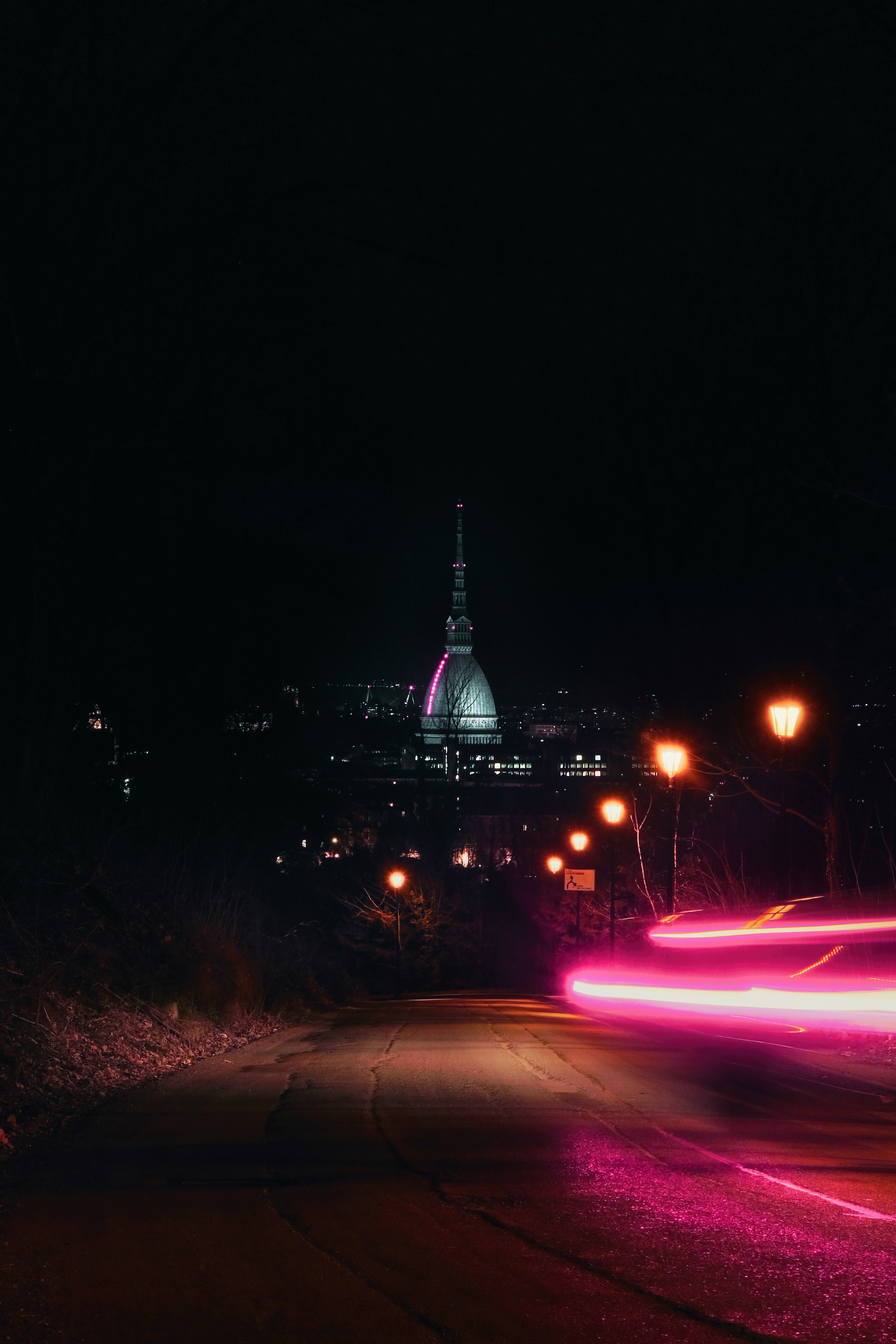 a city street at night with a car light streaking by