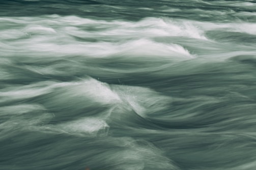Waves of water in motion, captured with a smooth, blurred effect, creating a serene and dynamic visual of flowing water.