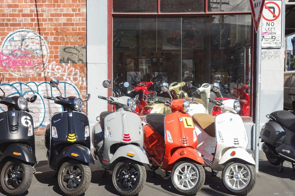 Una fila di scooter parcheggiati uno accanto all'altro di fronte a un edificio