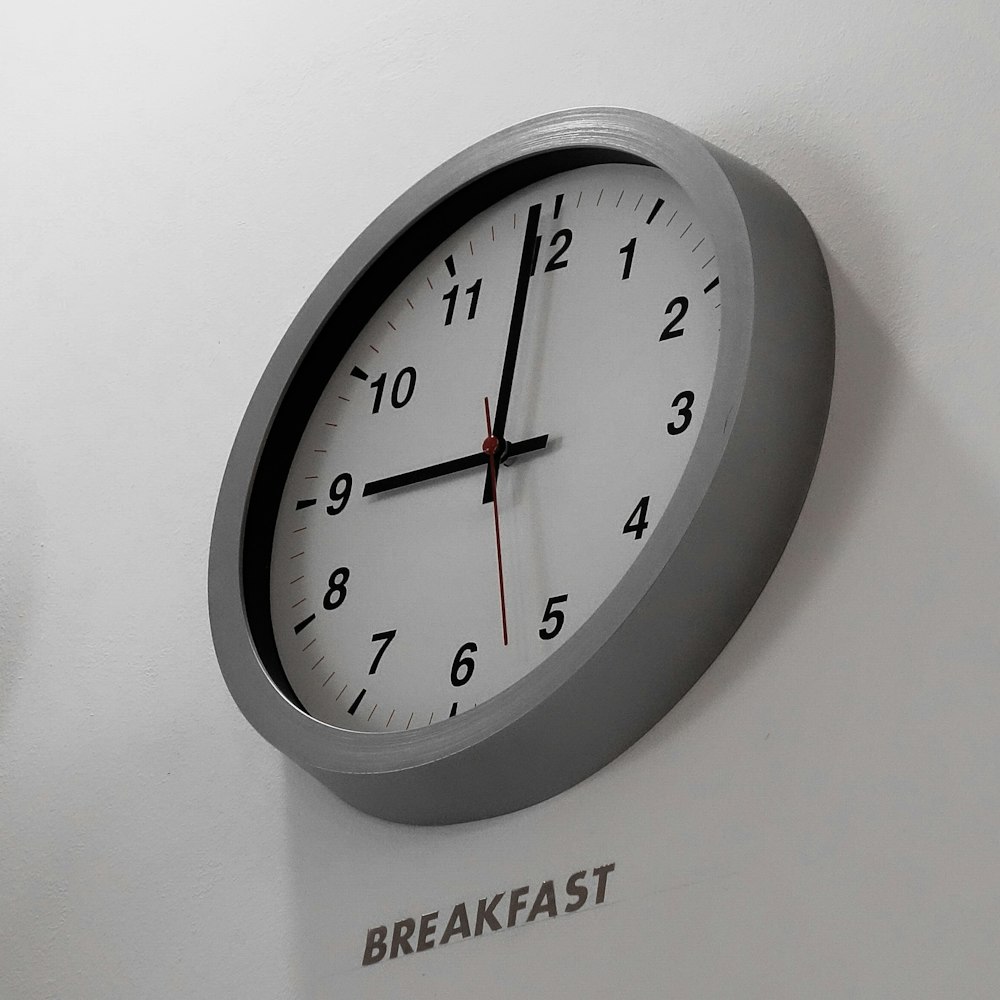 a clock mounted to the side of a white wall