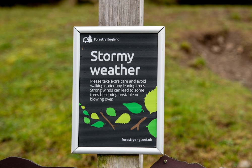 a sign posted on a wooden post in the grass