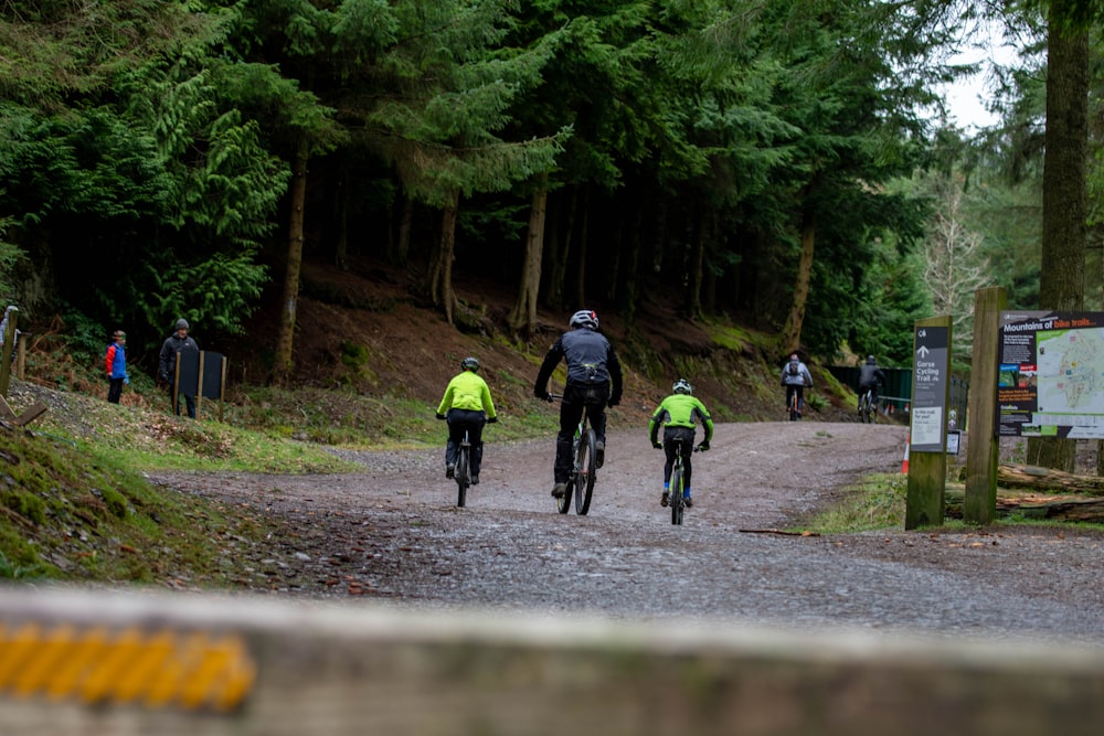 a couple of people riding bikes down a dirt road