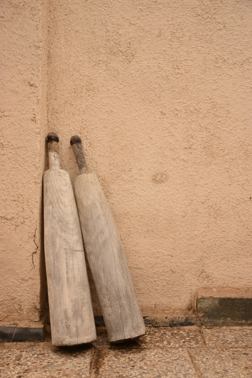 a pair of wooden baseball bats leaning against a wall