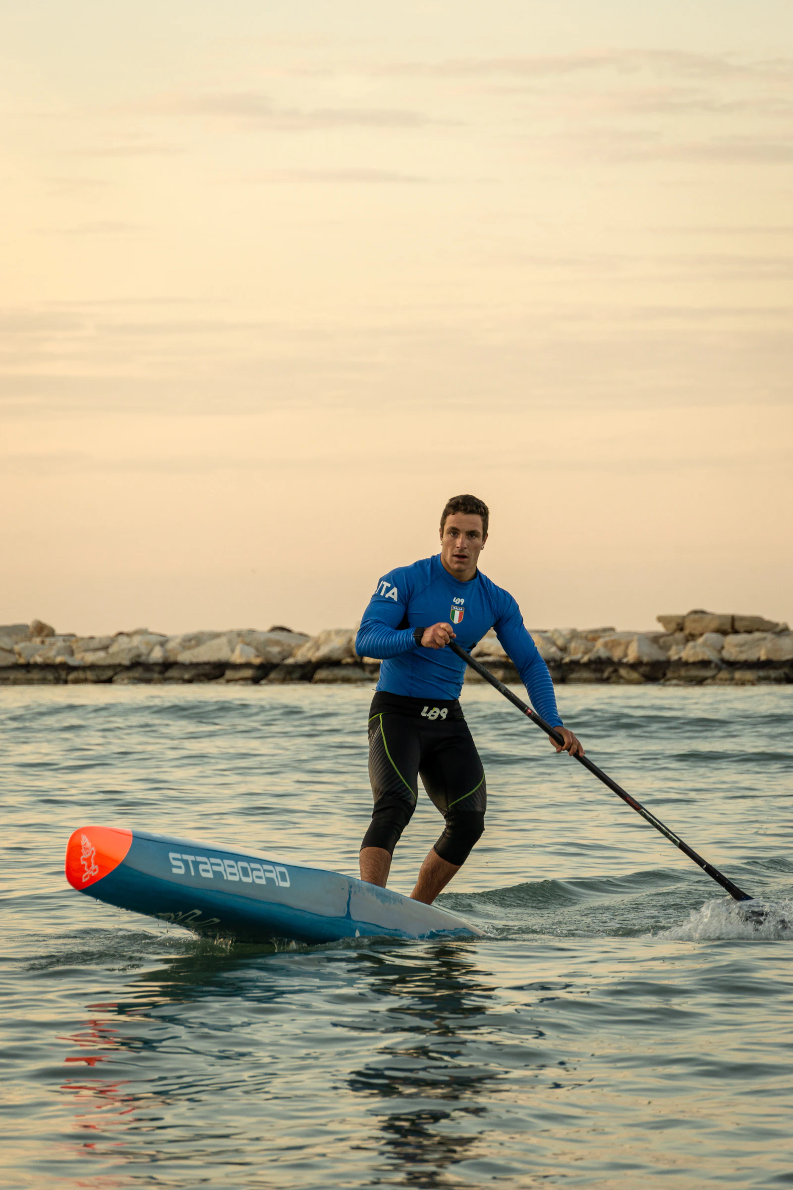 A real paddle board athlete standing on a paddle board on open water